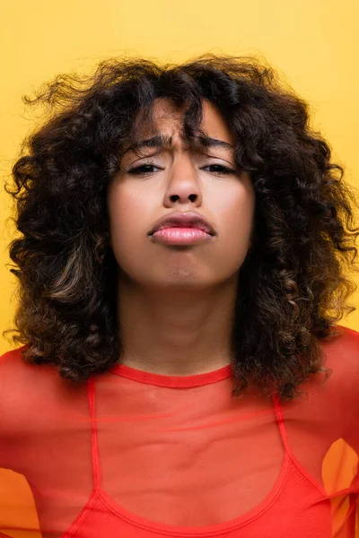 Ofendido afro-americano mulher bebendo lábios e olhando para câmera isolada no amarelo — Fotografia de Stock