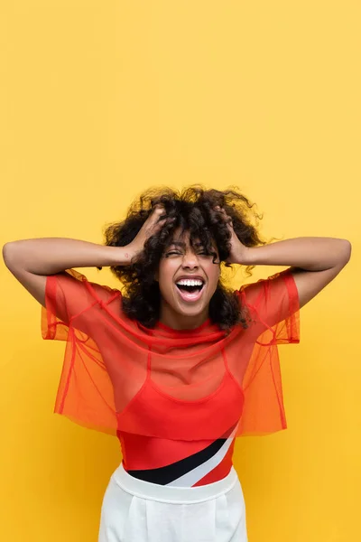 Excited african american woman with hands on head laughing with closed eyes isolated on yellow — Stock Photo