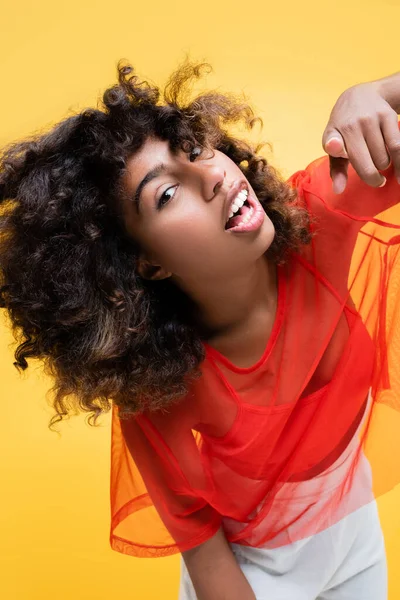 Eccitata donna afroamericana guardando la fotocamera e indicando con il dito isolato sul giallo — Foto stock