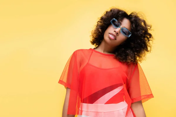 Afrikanisch-amerikanische Frau im stylischen Sommeroutfit und blauer Sonnenbrille isoliert auf gelb — Stockfoto