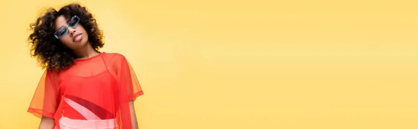 Bruna donna afroamericana in abiti estivi alla moda e occhiali da sole isolati su giallo, banner — Foto stock