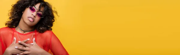 African american woman in stylish sunglasses touching chest and looking at camera isolated on yellow, banner — Stock Photo