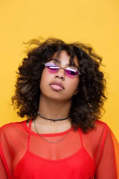 Ritratto di donna afroamericana con occhiali da sole alla moda e collane isolate sul giallo — Foto stock