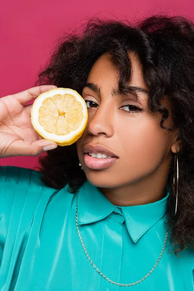 Morena afro-americana segurando meio limão perto do rosto isolado em rosa — Fotografia de Stock