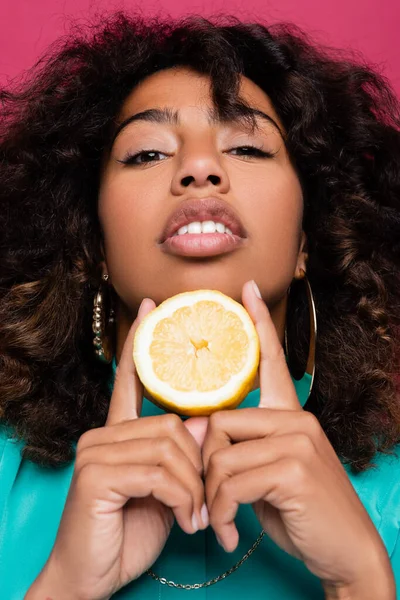 Femme américaine africaine bouclée posant avec moitié citron isolé sur rose — Photo de stock