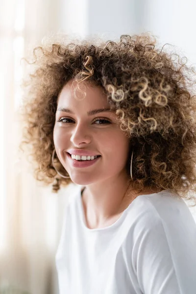 Porträt einer fröhlich gelockten Frau, die zu Hause in die Kamera schaut — Stockfoto