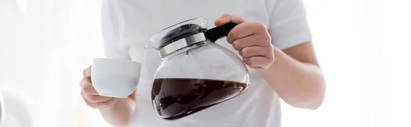 Vista recortada de la mujer vertiendo café en la taza blanca sobre fondo blanco, pancarta - foto de stock