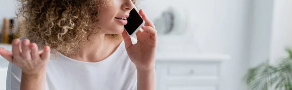 Partial view of woman with curly hair talking on mobile phone at home, banner — Stock Photo