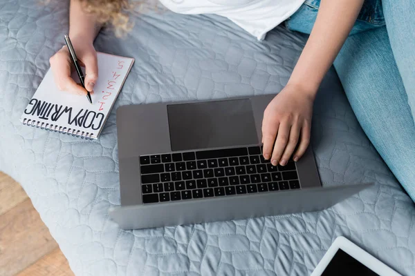 Vue du haut de la femme recadrée près d'un ordinateur portable et d'un ordinateur portable avec lettrage copywriting — Photo de stock