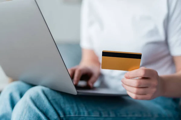 Visão parcial da mulher com cartão de crédito usando laptop em fundo embaçado — Fotografia de Stock