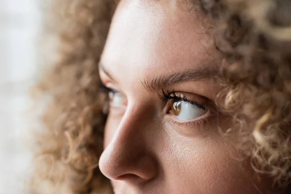 Частичный взгляд молодой женщины с вьющимися волосами и карими глазами — стоковое фото