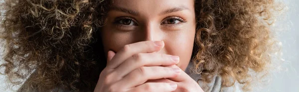 Jeune femme bouclée avec expression oculaire positive visage obscurcissant avec les mains, bannière — Photo de stock