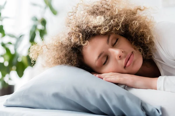 Young and curly woman sleeping on pillow in morning — Stock Photo