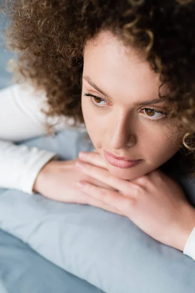 Vue rapprochée de la femme aux cheveux ondulés rêvant à la maison — Photo de stock