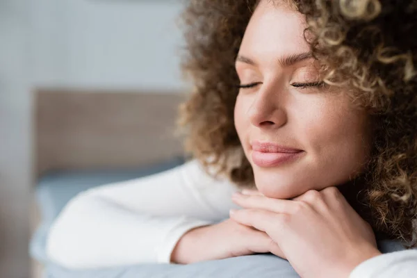 Vue rapprochée de la femme rêveuse souriant avec les yeux fermés dans la chambre — Photo de stock