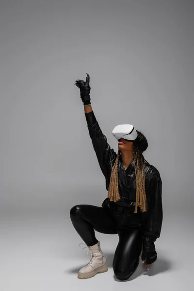 Afroamerikanerin in Handschuhen und vr Headset-Gaming auf grauem Hintergrund — Stockfoto