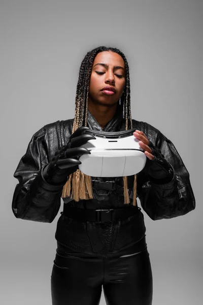 Stylish african american woman in leather jacket holding virtual reality headset isolated on grey — Stock Photo