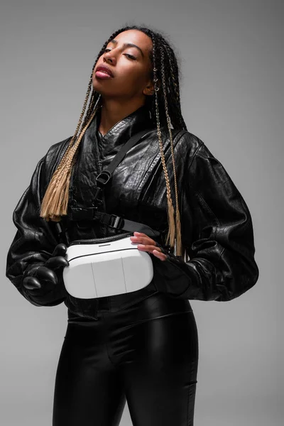 Portrait de femme afro-américaine en gants tenant un casque de réalité virtuelle isolé sur gris — Photo de stock