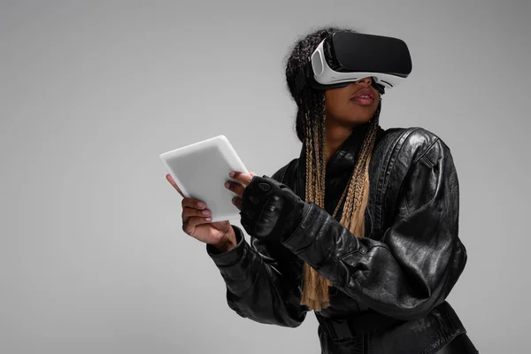 Donna afroamericana in auricolare vr con tablet digitale mentre giocava isolata sul grigio — Foto stock