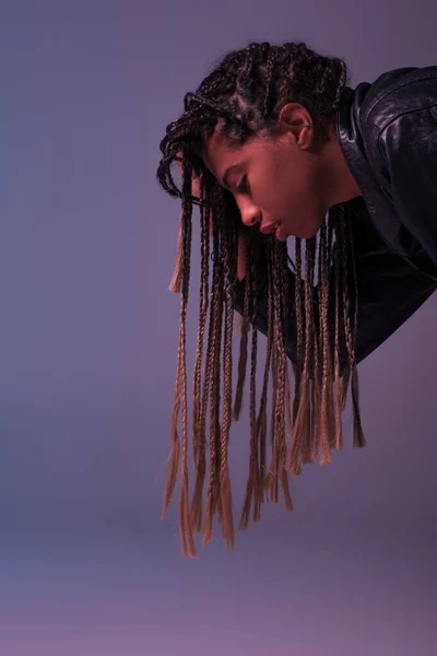 Side view of african american woman in leather jacket isolated on purple — Stock Photo