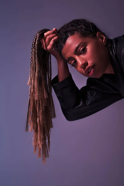 Stylish african aerican woman holding pigtails and looking at camera isolated on purple — Stock Photo