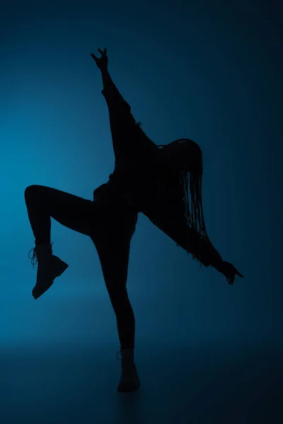 Silhouette of african american woman with pigtails moving on dark blue background — Stock Photo