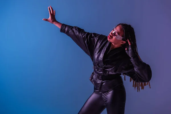 Stylish african american woman in smart glasses looking away on blue and purple background — Stock Photo