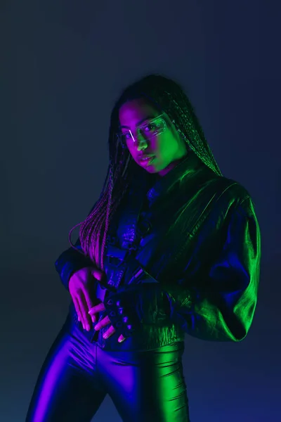 Stylish african american woman in smart glasses isolated on dark blue with lighting — Stock Photo