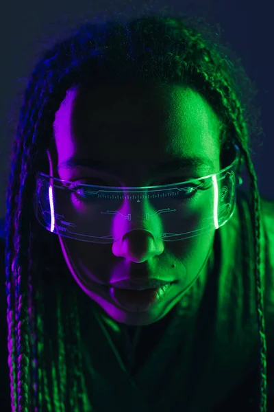 Portrait of african american woman with pigtails using smart glasses isolated on dark blue — Stock Photo