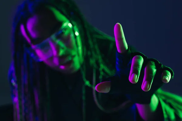 Blurred african american woman in smart glasses pointing with finger isolated on dark blue — Stock Photo