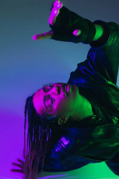 Vista de ángulo alto de la elegante mujer afroamericana en gafas inteligentes sobre fondo azul - foto de stock