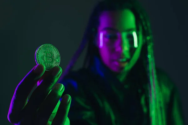 KYIV, UKRAINE - APRIL 28, 2022: Blurred african american woman holding bitcoin isolated on grey — Stock Photo