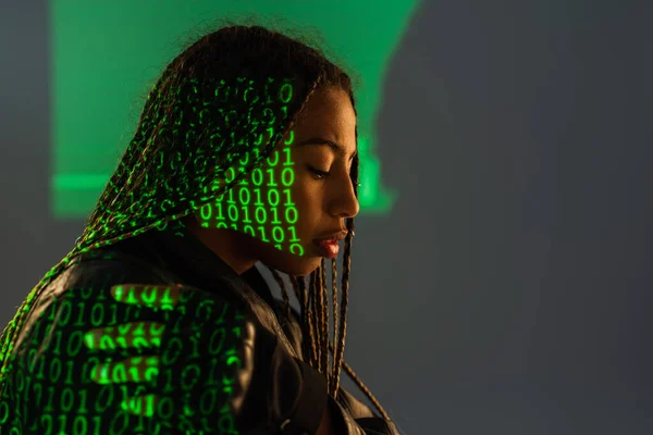 Side view of african american woman with projection of binary code on grey background — Stock Photo