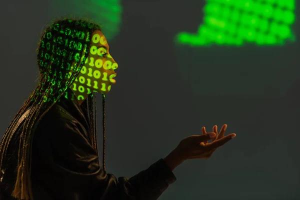 Seitenansicht einer afrikanisch-amerikanischen Frau mit Binärcode im Gesicht auf grauem Hintergrund — Stockfoto