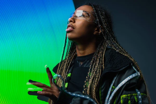 African american woman in smart glasses looking away near abstraction on grey background — Stock Photo