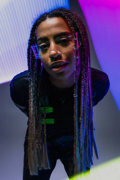 African american woman in smart glasses looking at camera on abstracted colorful background — Stock Photo