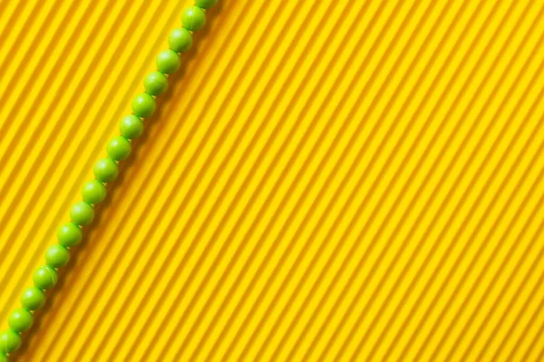 Top view of line of green balls on yellow striped background — Stock Photo