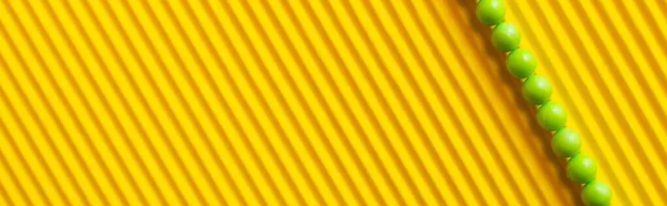 Top view of small green balls on striped yellow background with copy space, banner — Stock Photo