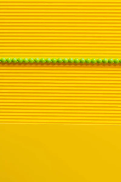 Draufsicht auf grüne Kugeln in horizontaler Reihe auf gelbem strukturierten Hintergrund — Stockfoto