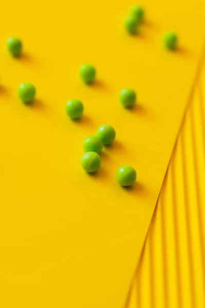 Vista de ángulo alto de pequeñas bolas verdes sobre fondo amarillo y borroso - foto de stock