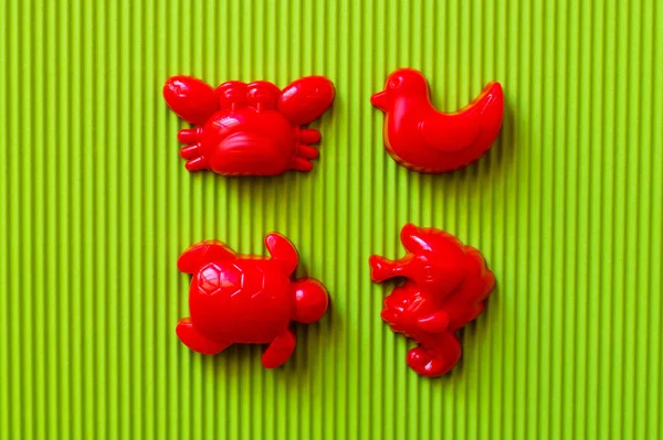 Vista superior de animales de mar rojos y juguetes de pato sobre fondo corrugado verde - foto de stock