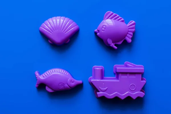 Vista superior de las formas plásticas en forma de animales marinos y barco sobre fondo azul - foto de stock