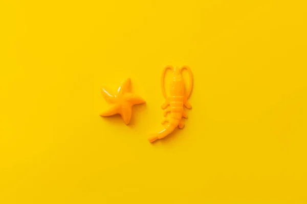 Top view of bright plastic shrimp and starfish on yellow background — Stock Photo