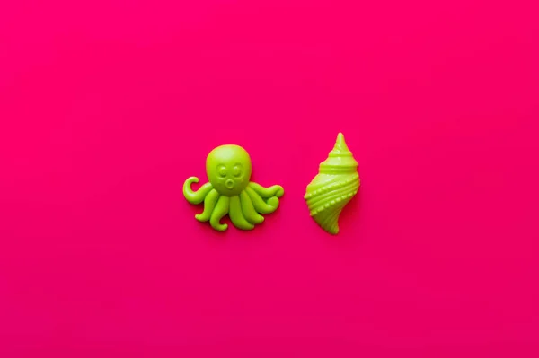 Вид сверху на зеленого осьминога и игрушки из моллюсков на розовом фоне — стоковое фото
