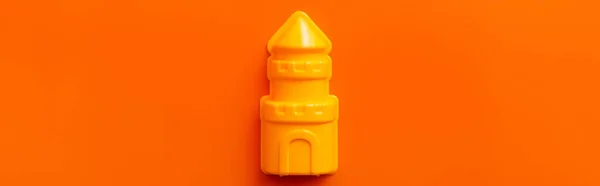 Vista superior de la torre de juguete amarillo sobre fondo naranja, bandera - foto de stock