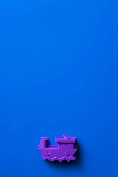 Vista superior de la nave de juguete púrpura sobre fondo azul con espacio de copia - foto de stock
