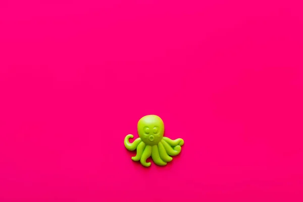 Top view of green plastic octopus on pink background — Stock Photo