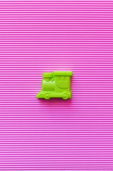 Top view of bright green toy locomotive on violet textured background — Stock Photo