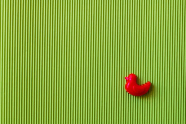 Vista superior del molde rojo en forma de pato sobre fondo texturizado verde - foto de stock