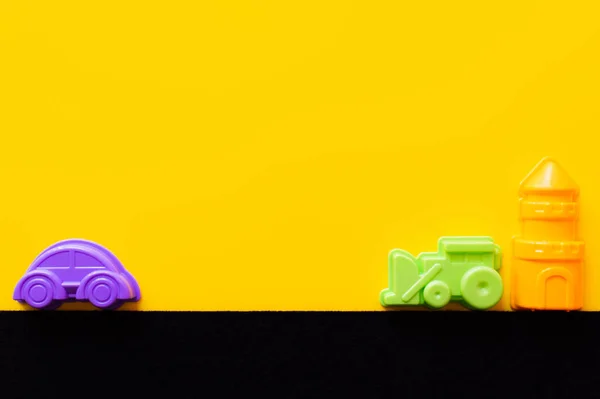 Vista superior de la torre de juguete cerca de coloridos vehículos de plástico sobre fondo negro y amarillo — Stock Photo